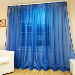 The image shows blue transparent curtains, made of tulle, hanging in front of a window.