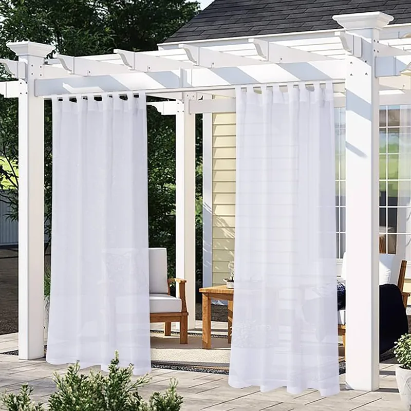 Two white, sheer, waterproof outdoor curtains hang from a white pergola.