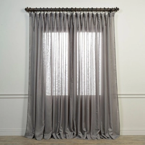 Grey sheer curtains with soft pleats hanging over a window.