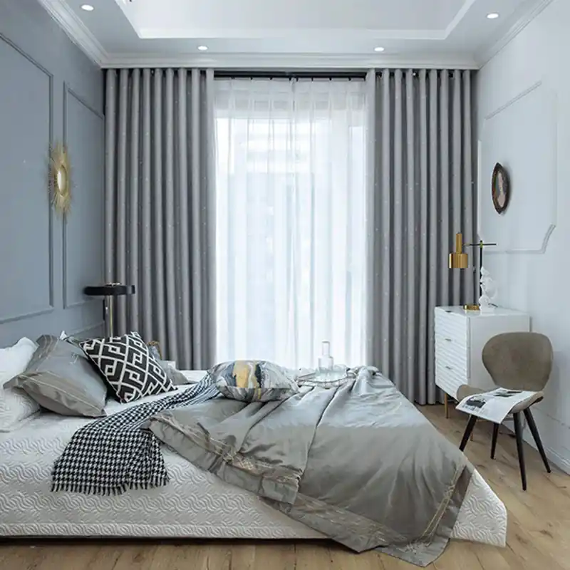 A stylish bedroom with grey curtains and bedding